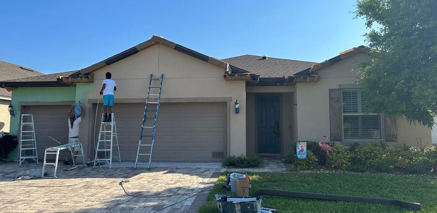 Same home mid-paint, crew on ladders working detail